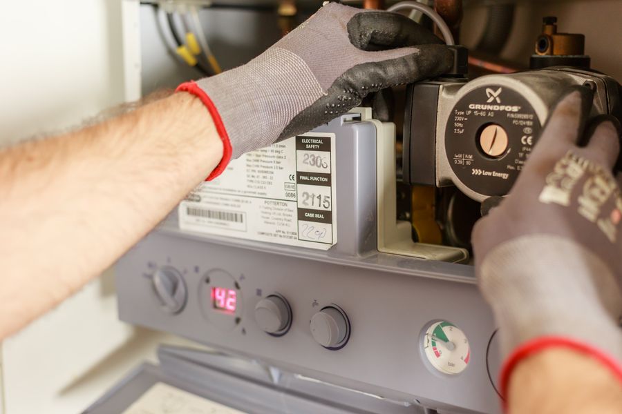 Gloved hands servicing a heating and plumbing pump